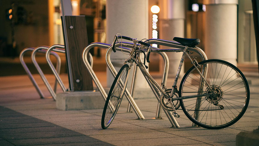Una sola bicicleta asegurada a un moderno anclaje comercial fuera de un edificio bien iluminado por la noche