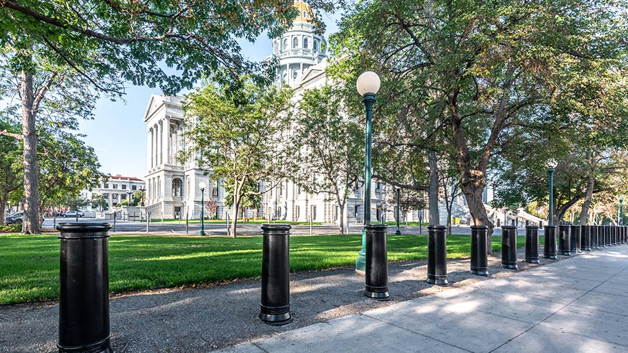 Row of custom Reliance Foundry crash-rated bollards installed along a sidewalk near the Colorado State Capitol building.