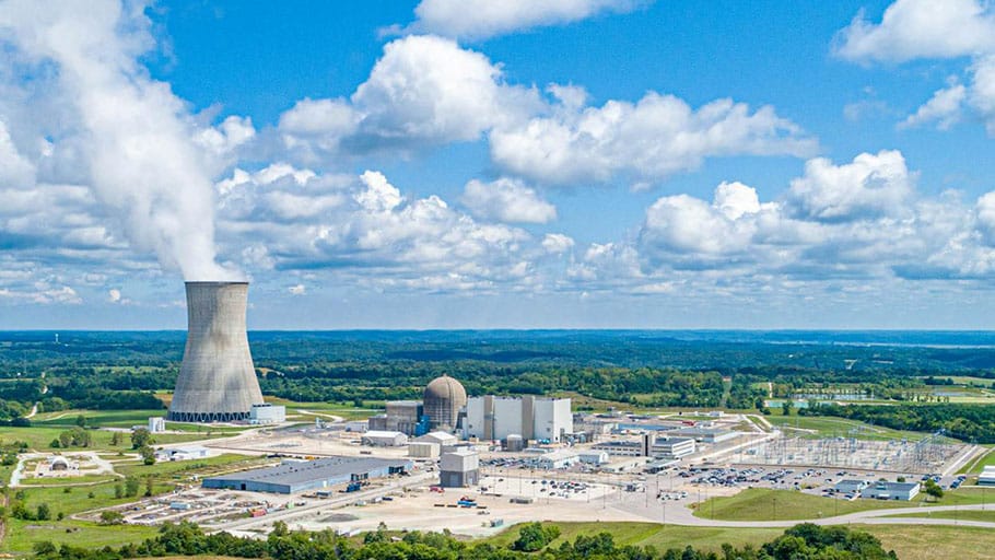 Vista aérea de una planta de energía nuclear con una torre de enfriamiento emitiendo vapor.