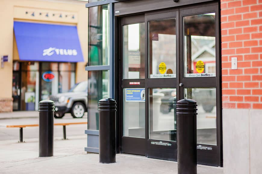 Thick black bollards in steel metal covers protect an electronics store