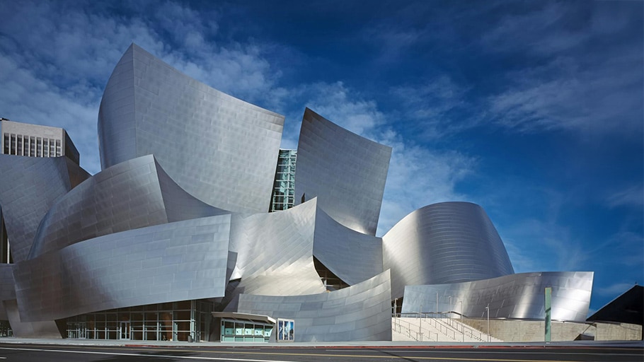 Curved stainless steel façades shimmer beneath a blue sky, illustrating how premium satin finishes elevate modern architecture.