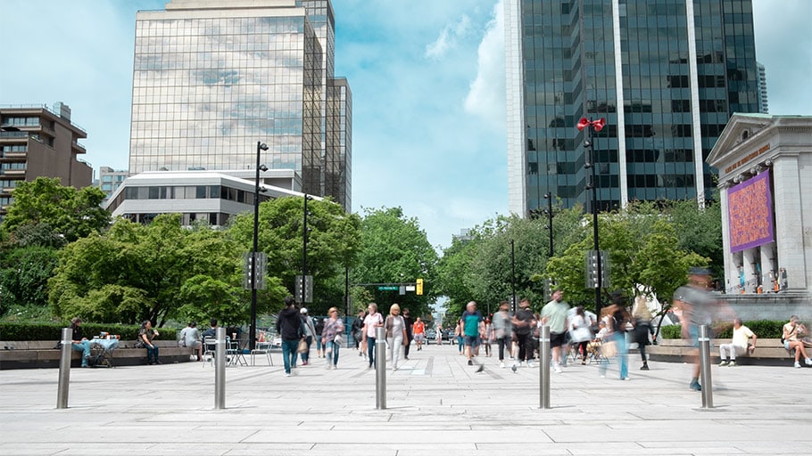 The Vancouver Art Gallery with trees, modern buildings, and bollards for traffic control.