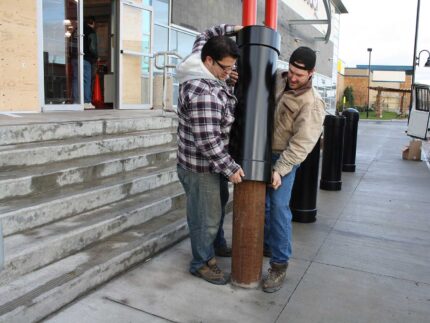 Two men installing R-1007-10 steel pipe security bollard