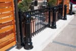 Three R-7539 decorative bollards along iron fence