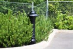 R-7552 decorative bollard by curb near green bushes