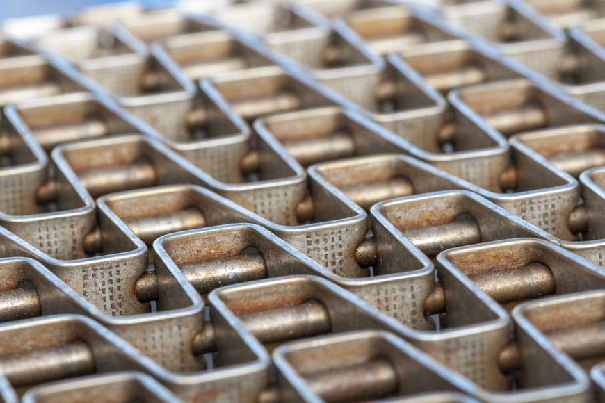 Stainless steel conveyer belt made of interlocking segments shows some signs of corrosion