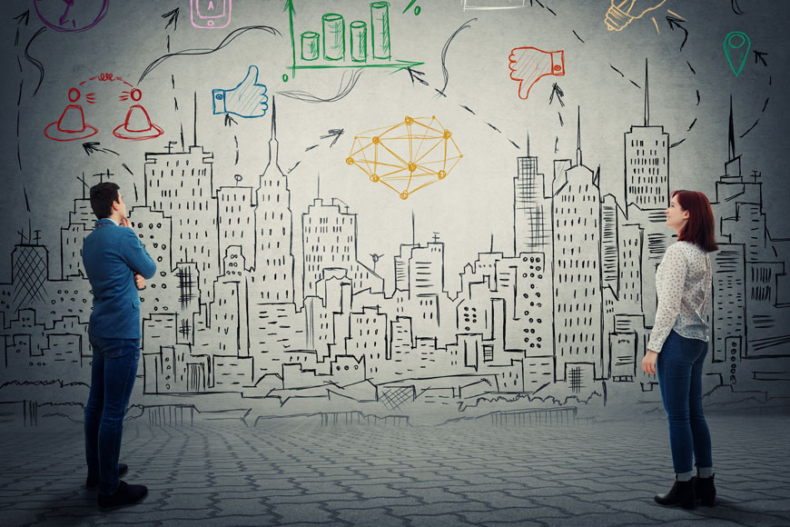 Composite picture: two young urban planners stand before a drawn city map with icons of cost and traffic management