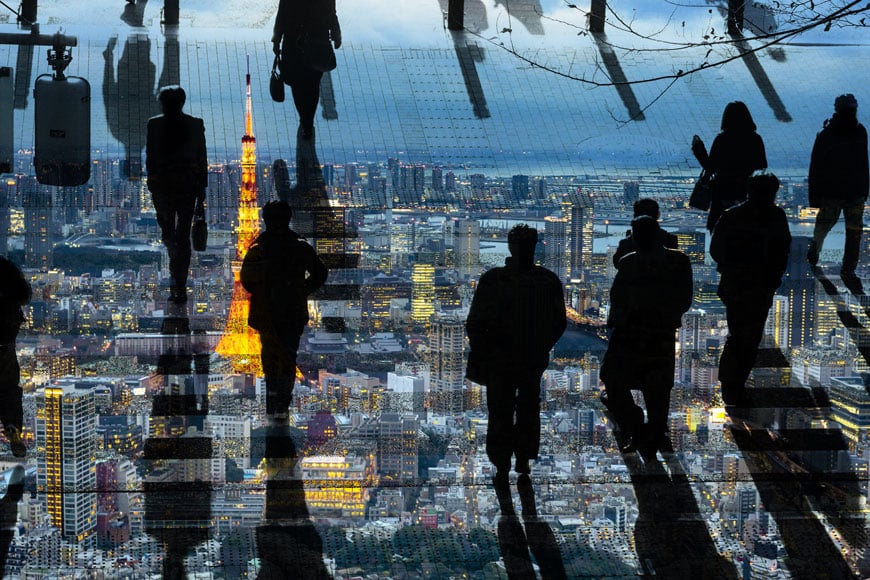 A shot of people walking over cobblestones with trench grating is overlaid on a nighttime aerial shot of Paris.
